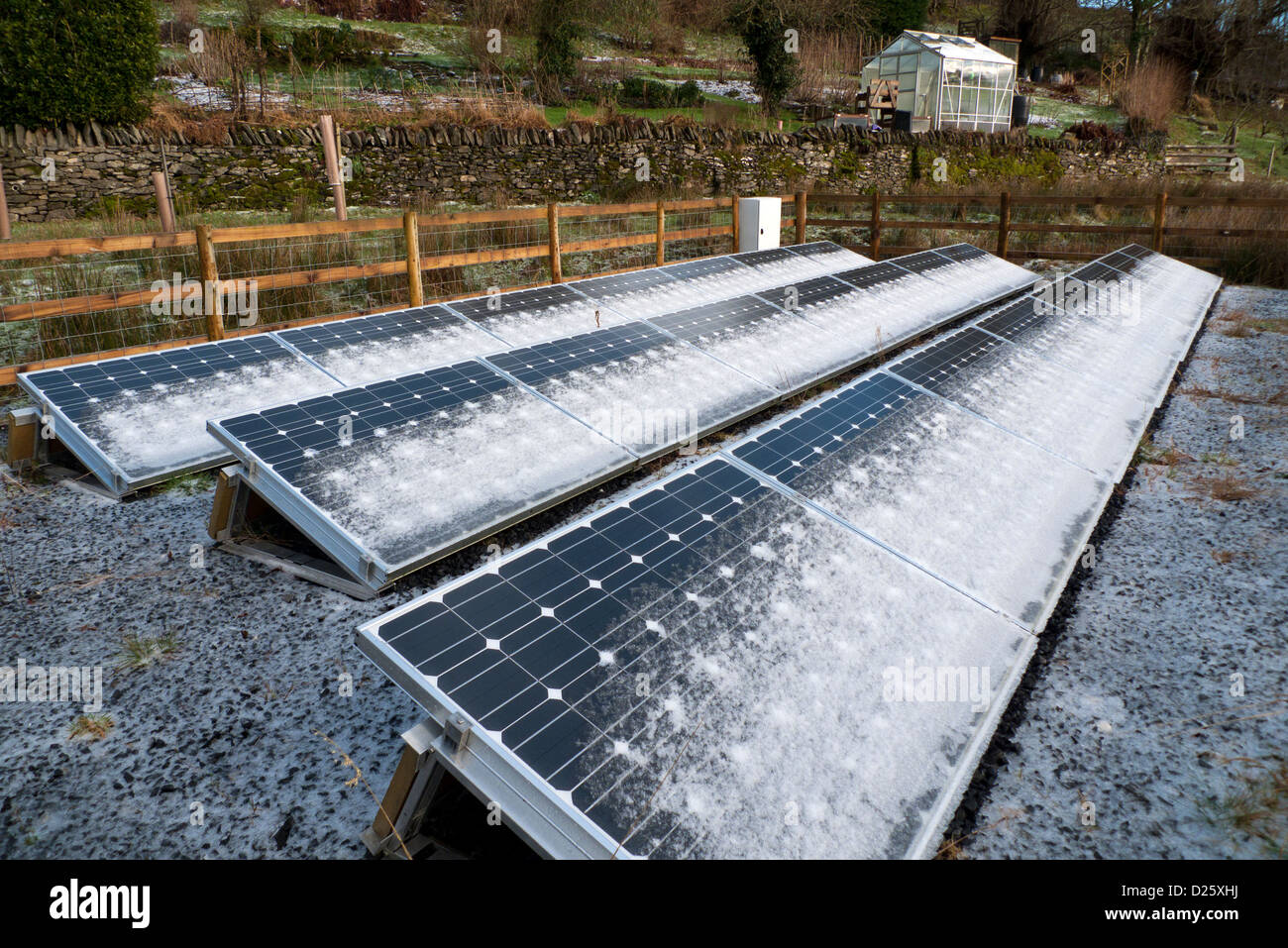 Snow frost on free standing solar panels panel and greenhouse in winter January garden on smallholding in West Wales, UK   KATHY DEWITT Stock Photo