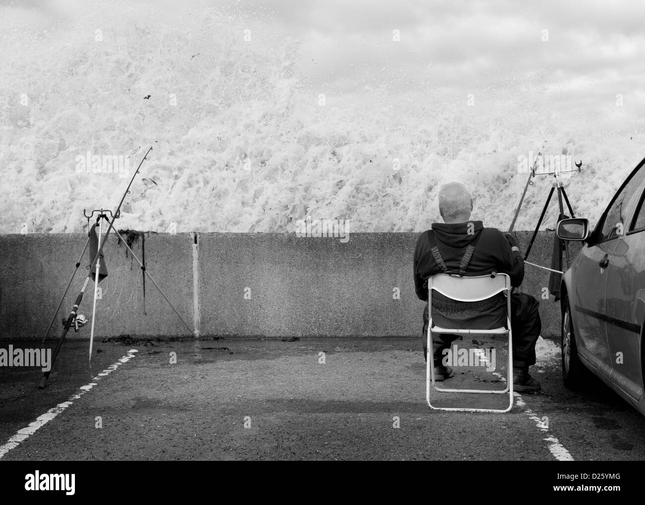A Fisherman Sits Behind A Sea Wall During Heavy Seas At Sandsend Near