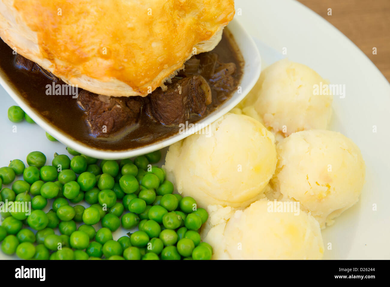 Tasty looking meat pie served with mashed potatoes and peas. Stock Photo