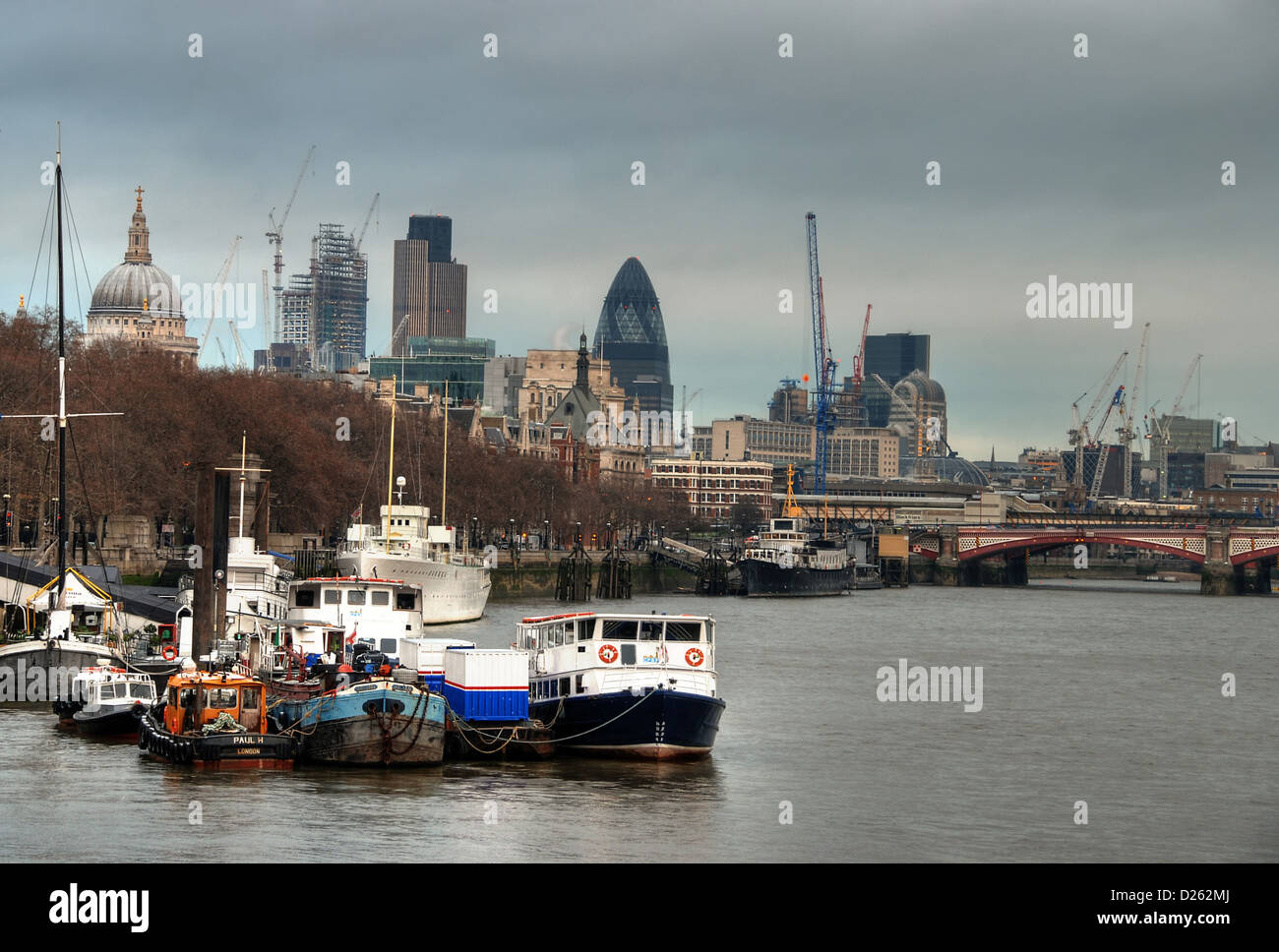 The City of London, seen behind boats on the River Thames Stock Photo