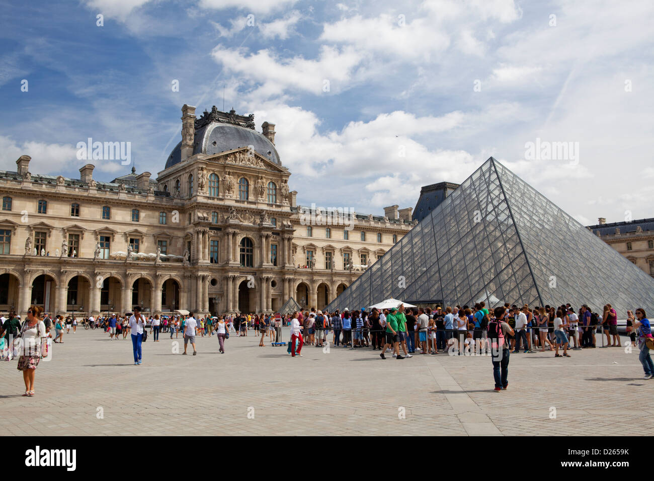 Louvre palace with its Pyramid gate and tourists waiting in line to get