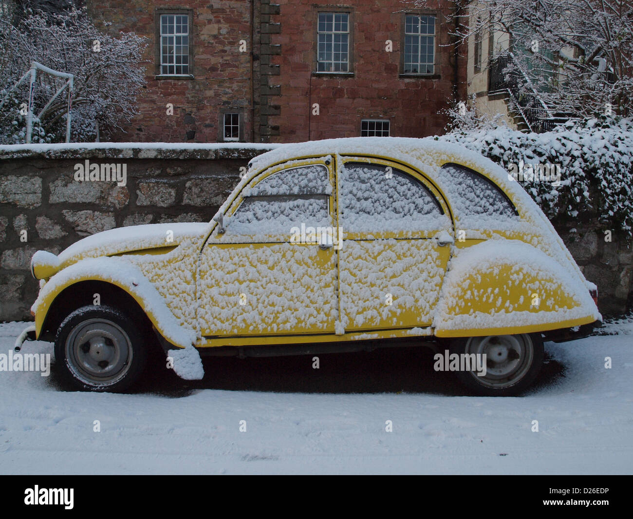 A yellow Citroën 2CV, covered in snow, parked in the Scottish Highland town of Cromarty. Stock Photo