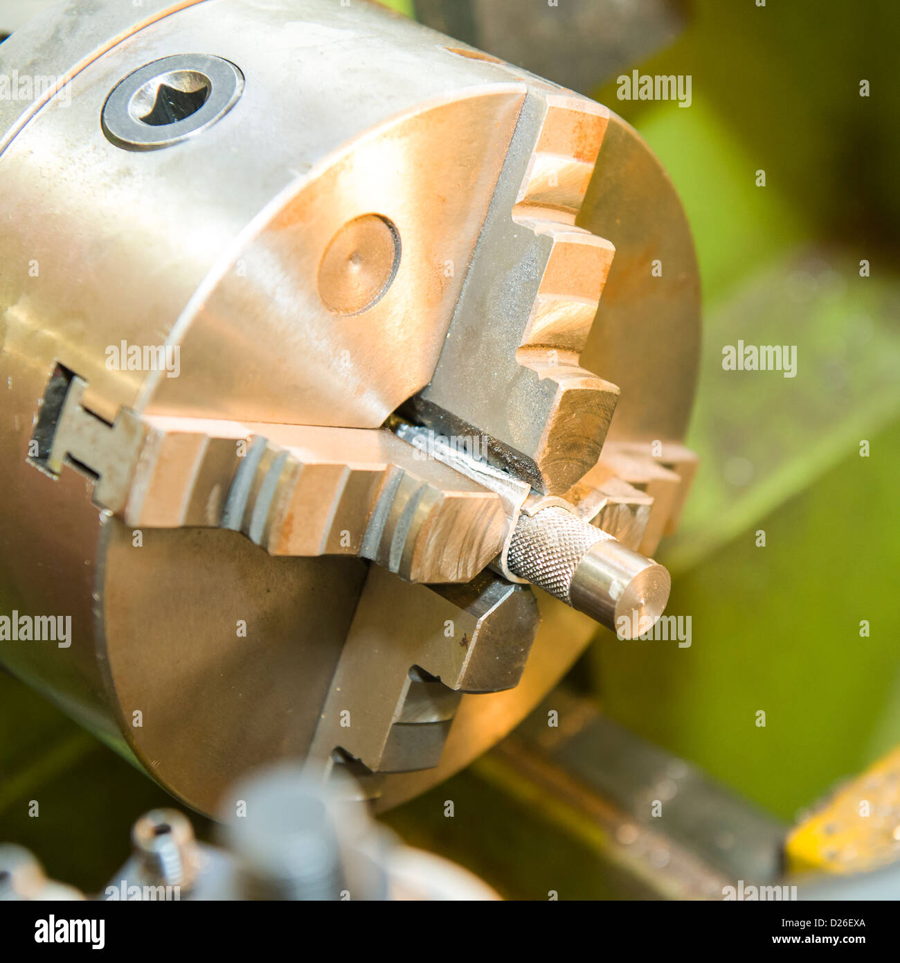 A metal part held in an industrial metal turning lathe using a four jaw chuck Stock Photo