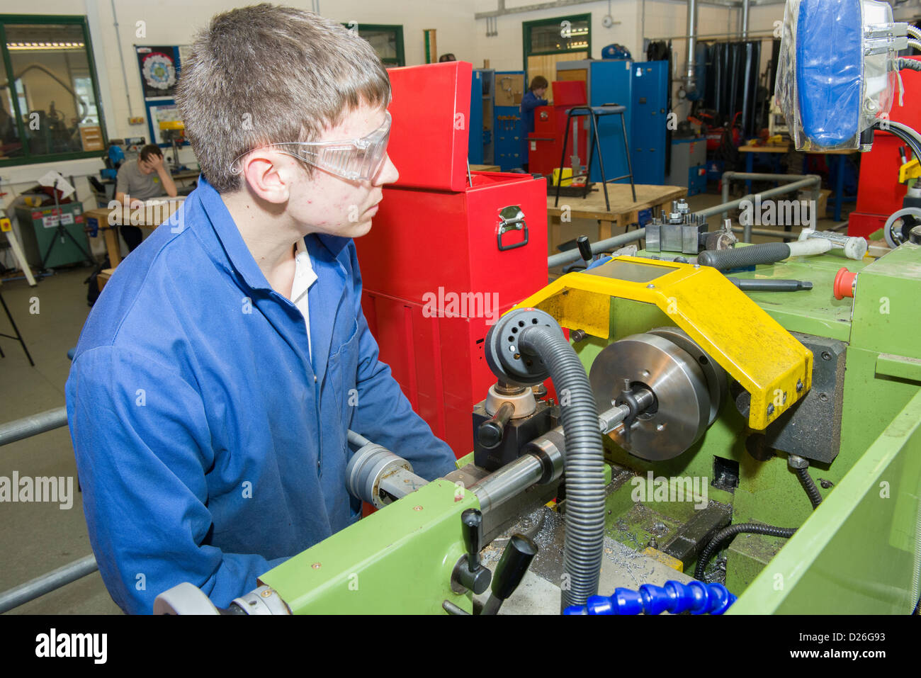 An engineering student working on a metal turning lathe in a school or