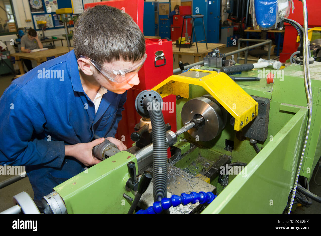 An engineering student working on a metal turning lathe in a school or ...