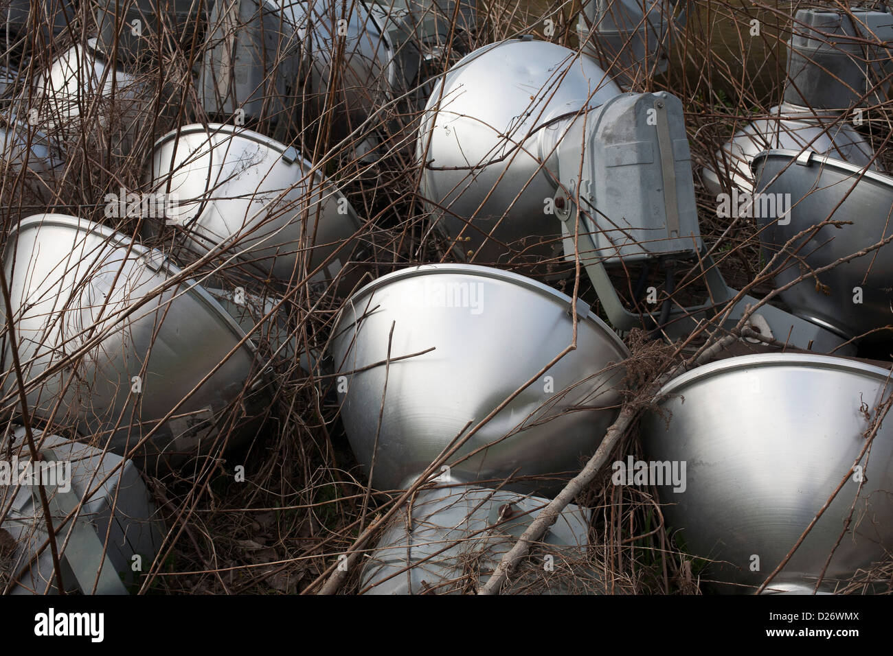 Street lamps lie abandoned in the weeds in a municipal dumping area. Stock Photo