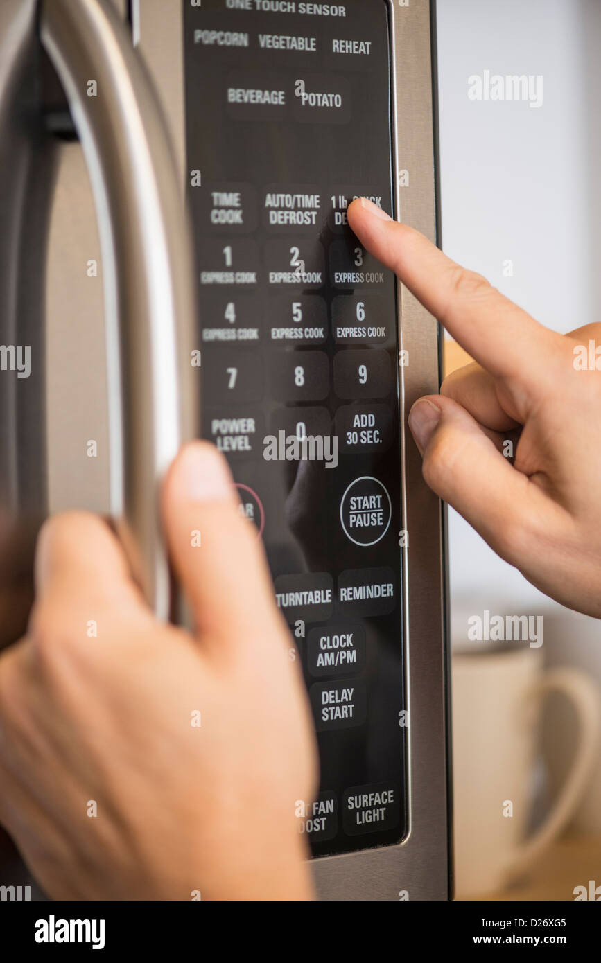 USA, New Jersey, Jersey City, Close-up of hand using microwave oven Stock Photo