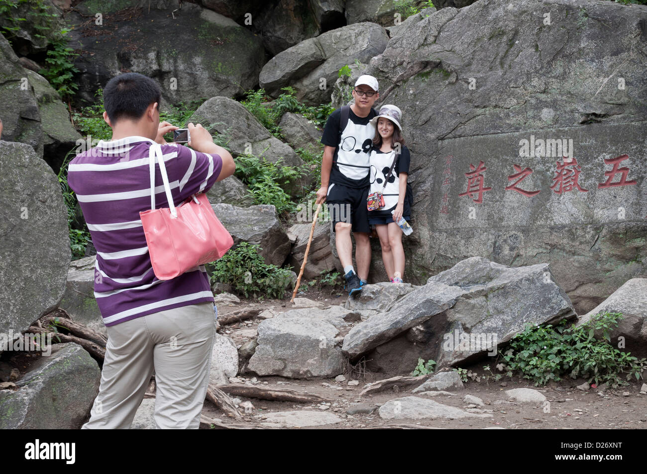 A matching couple pose next to one of the many inscriptions on the climb to the top of Tai Shan, China Stock Photo