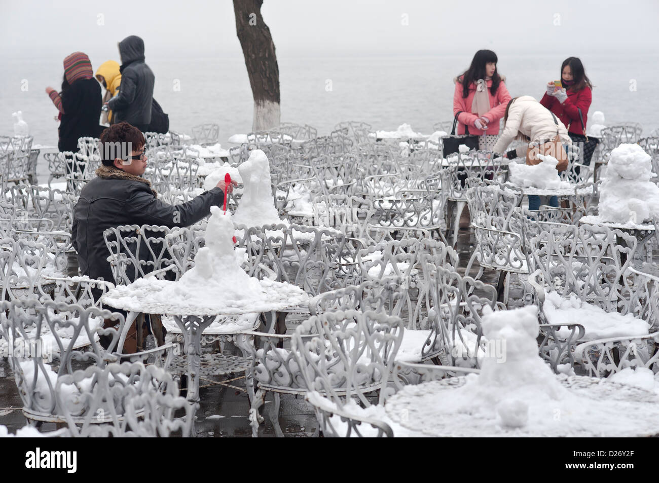 Young Chinese visitors sculpt snowmen on tables outside a lakeside restaurant during winter at West Lake, Hangzhou Stock Photo