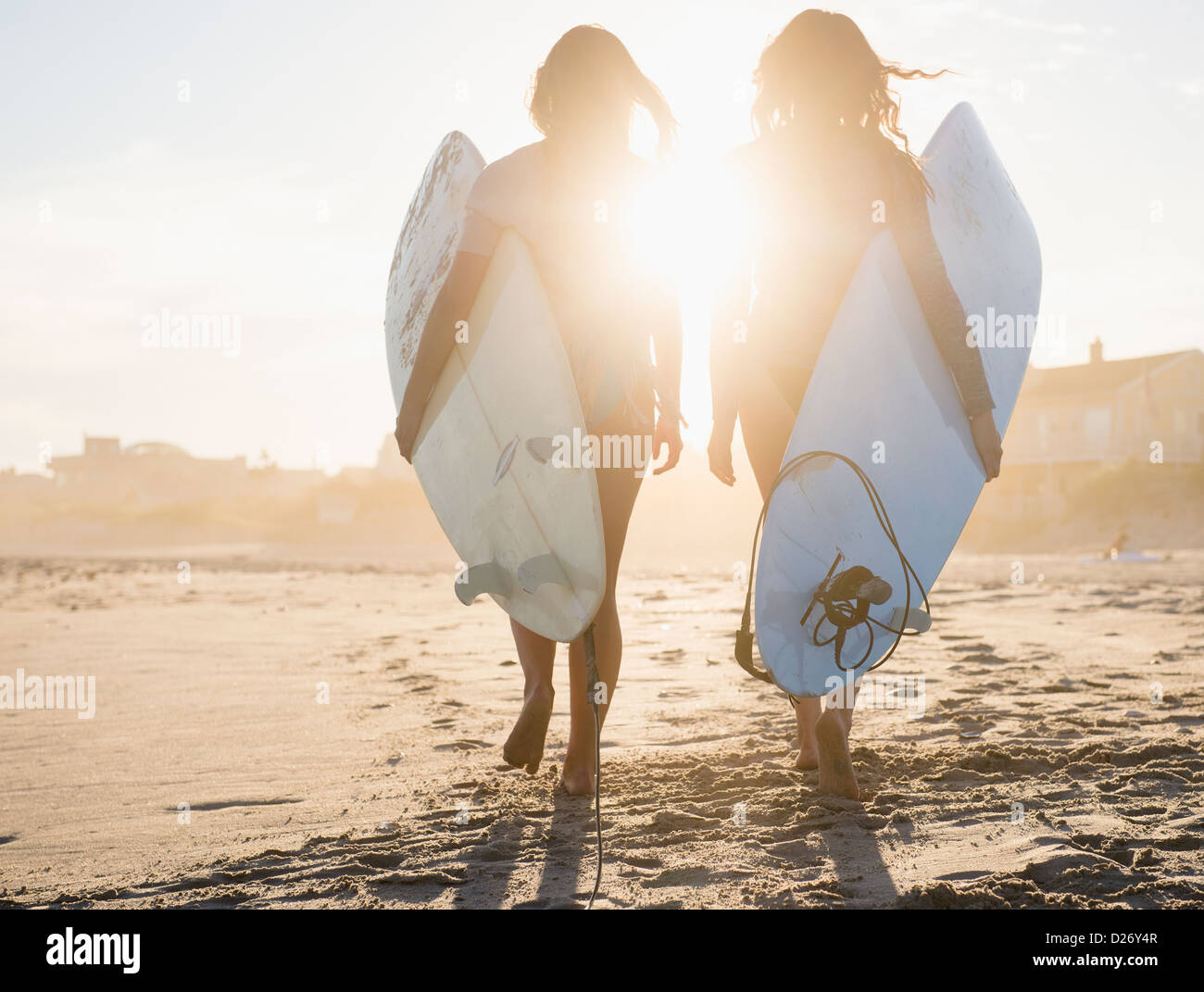 USA, New York State, Rockaway Beach, Two female surfers walking on beach at sunset Stock Photo