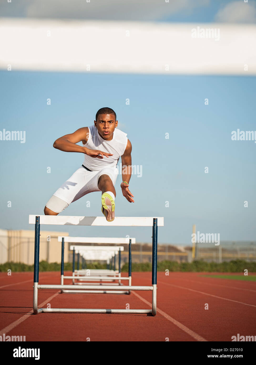 USA, California, Fontana, Boy (12-13) hurdling on running track Stock Photo