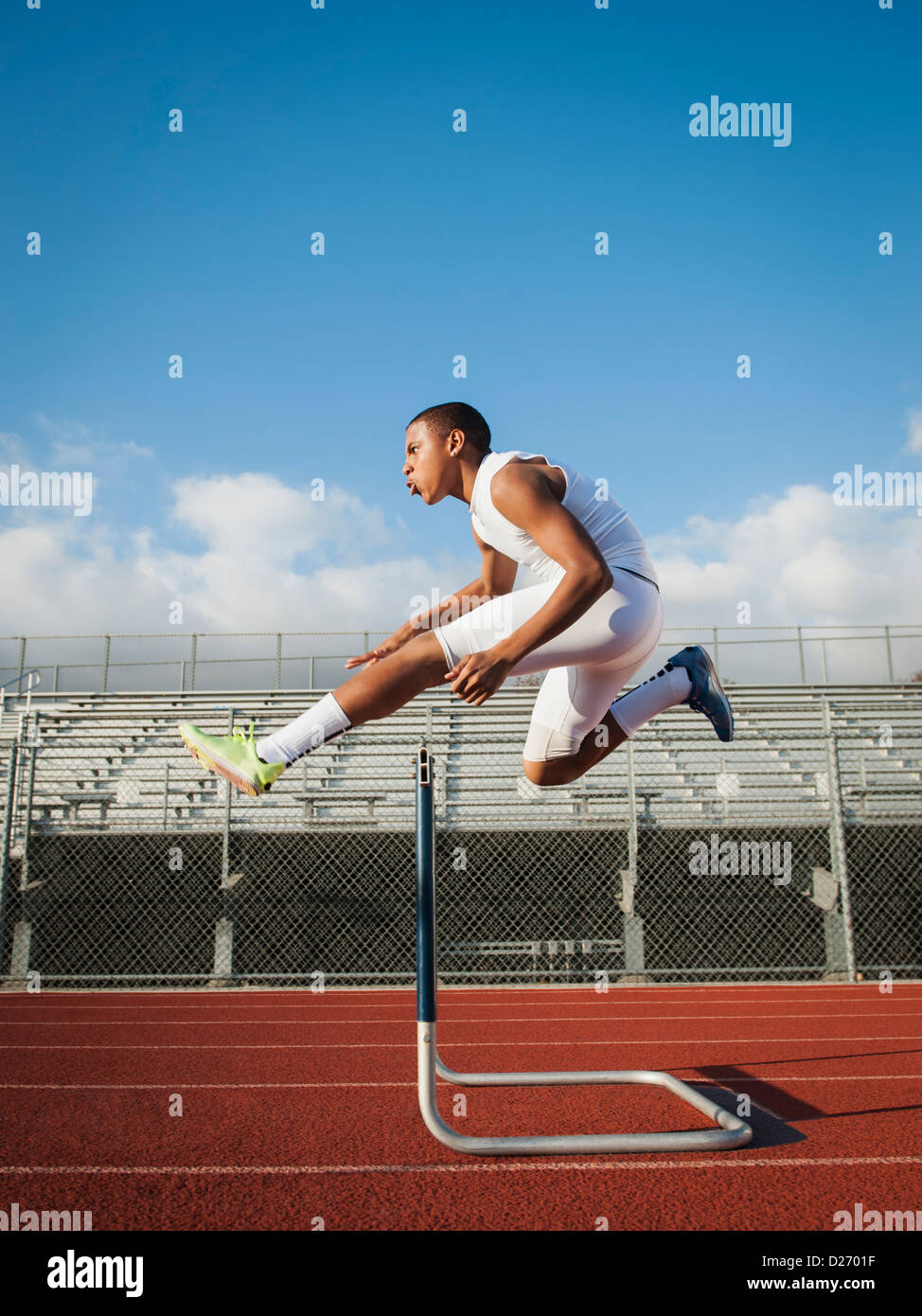 USA, California, Fontana, Boy (1213) hurdling on running track Stock