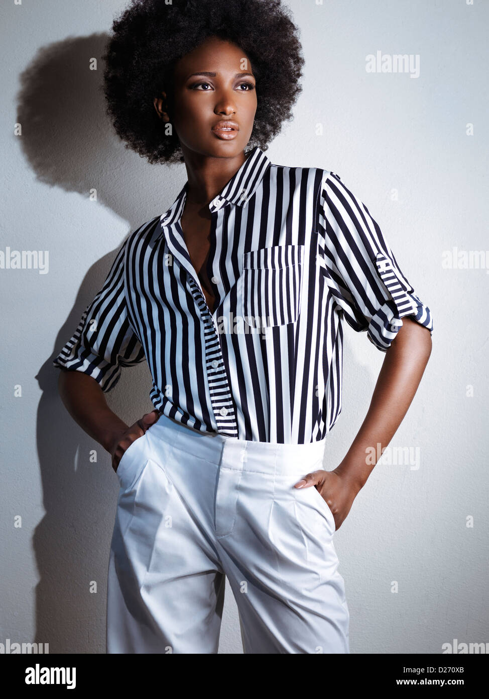 Beautiful young african american black woman wearing white pants and a stripy shirt. Artistic fashion photo. Stock Photo