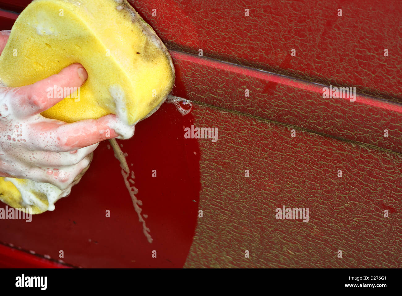 Cleaning the dirty car by hand with a yellow soapy sponge better than automatic car wash Stock Photo