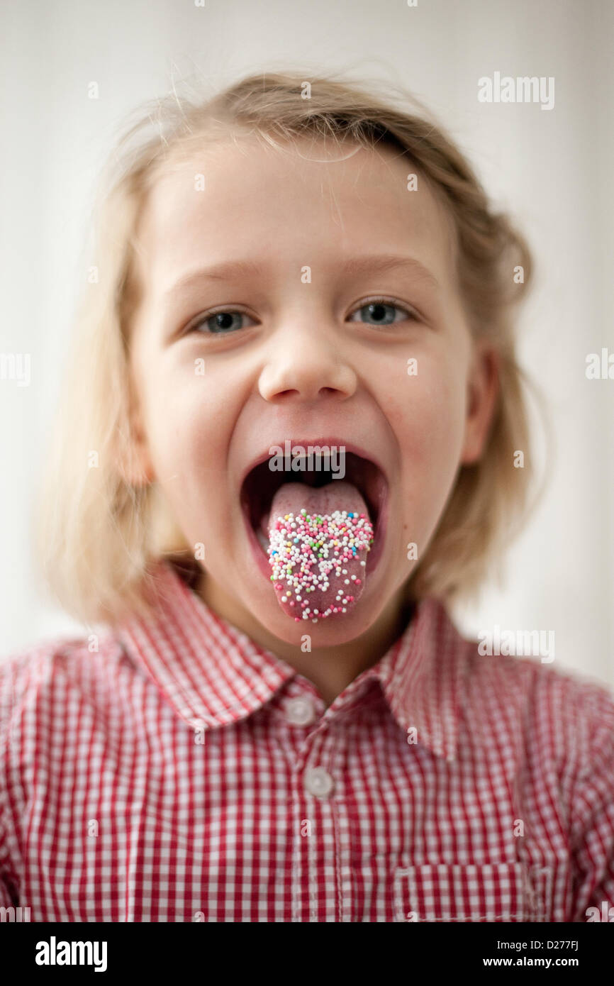 A little girl has her tongue full of Hundreds and Thousands Stock Photo