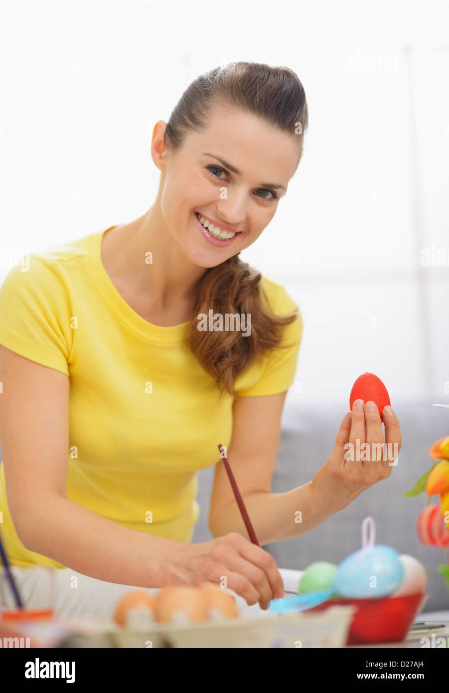 Smiling young woman preparing Easter red eggs Stock Photo