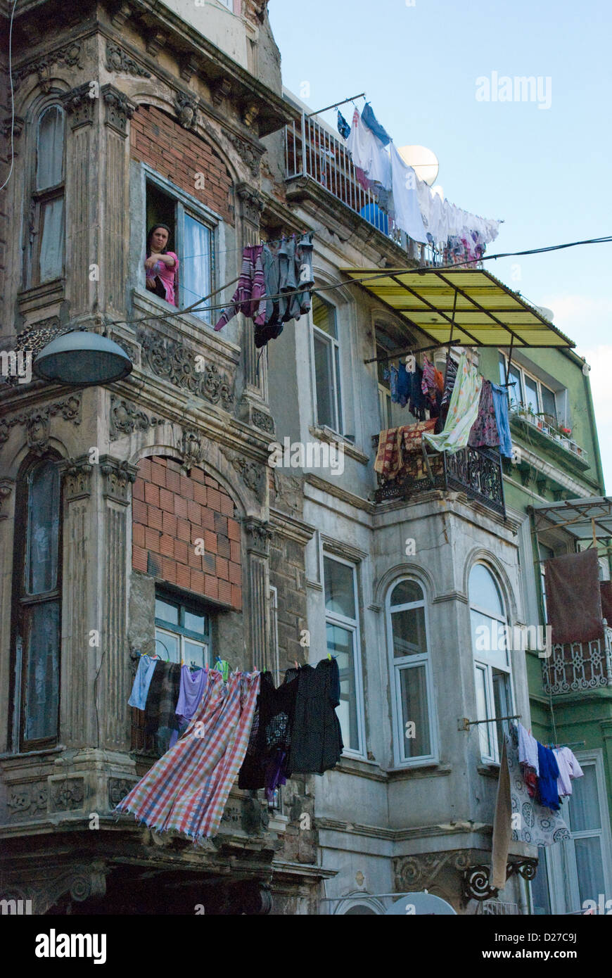 A woman at her window overlooking street in poor district Tarlabasi, Istanbul. Locals hang their washing out across the street. Stock Photo