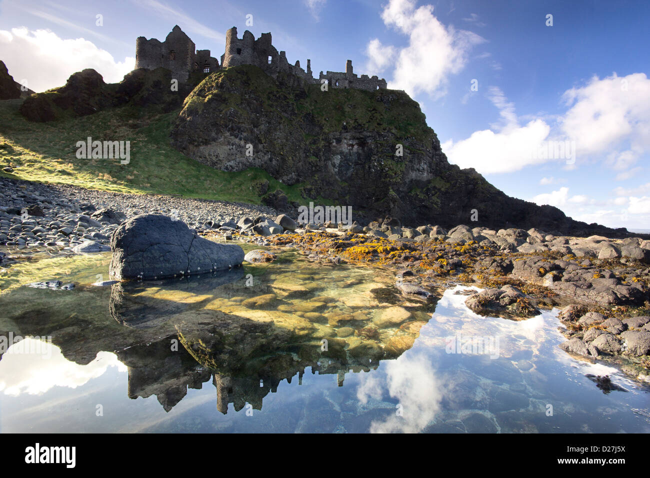 The famous Dunluce Castle - a UNESCO landmark from the Causeway Coast of Northern Ireland - reflected in a tidal pool. Stock Photo