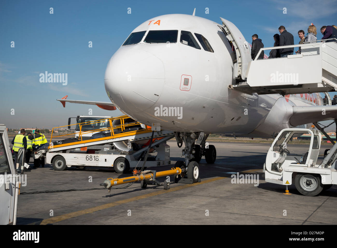 Luggage bags being loaded onto an aircraft and passengers boarding Stock Photo