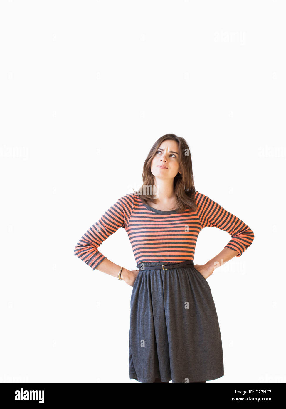 Studio shot young woman with hands on hip looking up Stock Photo - Alamy