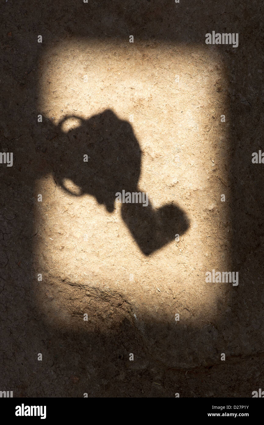 Shadow of Indian girls hand holding heart shape on textured ground in india Stock Photo