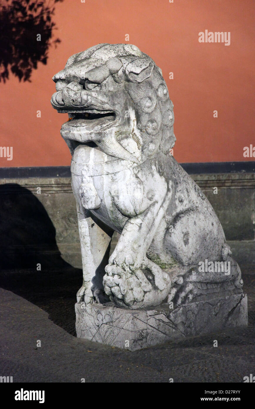 It's a photo of a Chinese LIon statue or sculpture in stone near the entrance of a temple. it's to protect from bad spirits Stock Photo