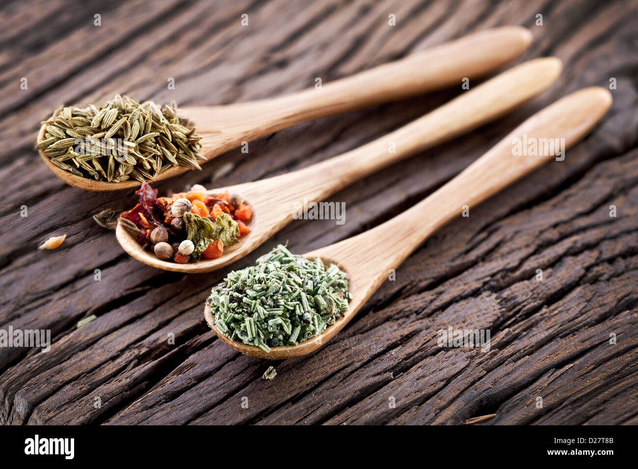 Variety of spices in the spoons on an old wooden table. Stock Photo