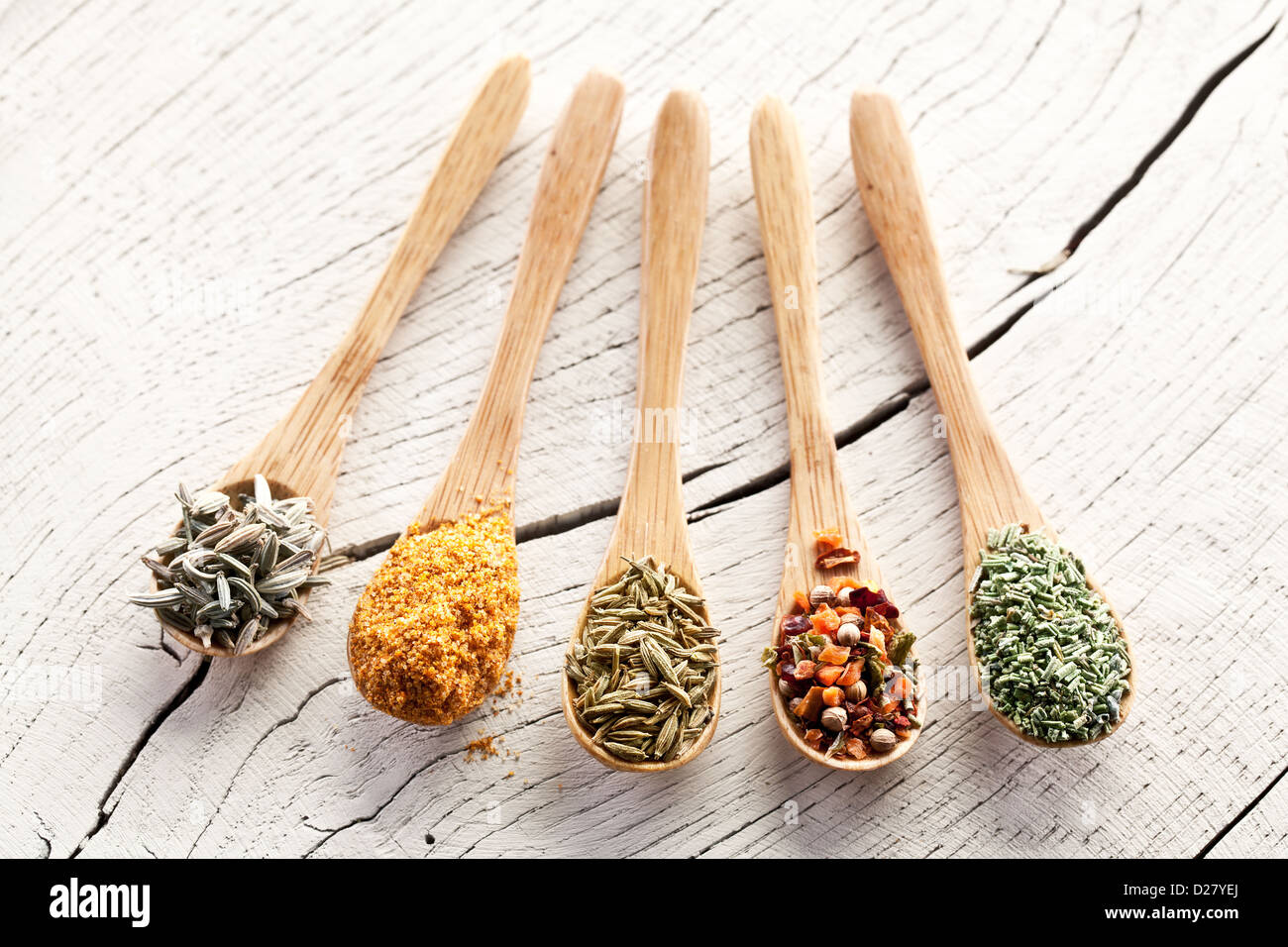 Variety of spices in the spoons on an white old wooden table. Stock Photo
