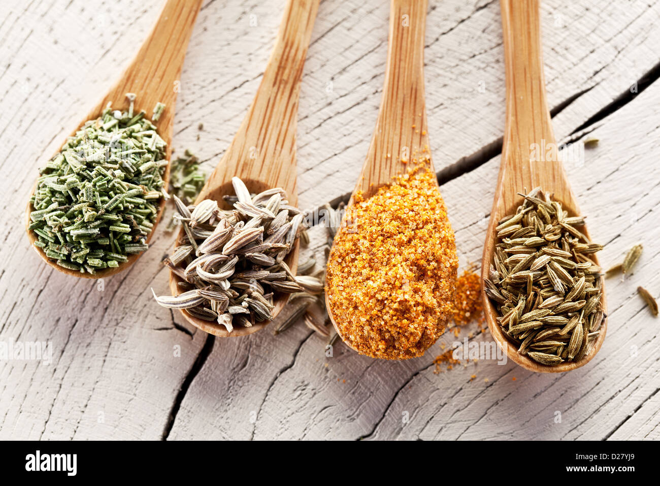 Variety of spices in the spoons on an white old wooden table. Stock Photo