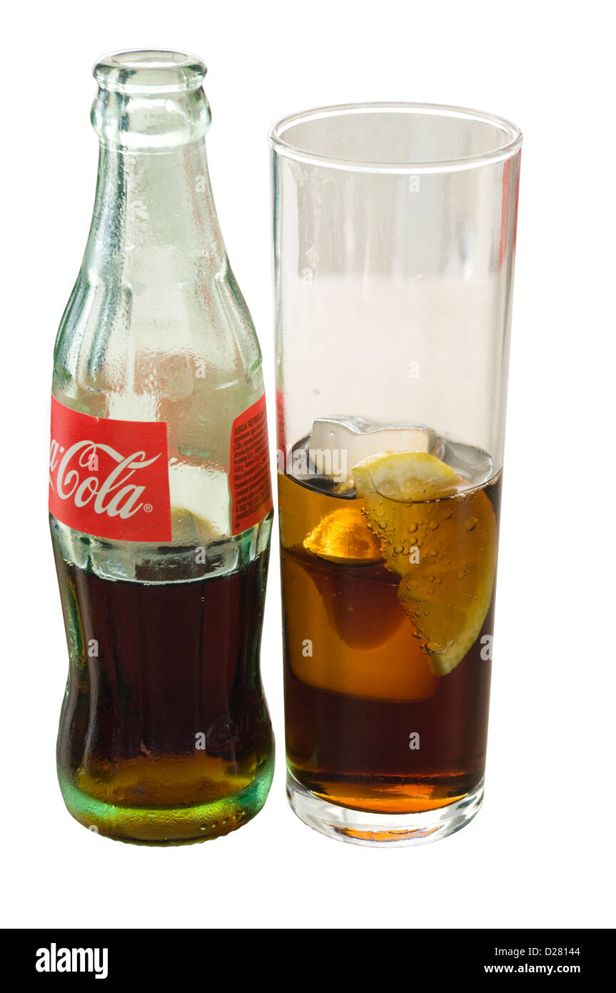 Glass Bottle Of Coca Cola next to A Glass Of Coca Cola With Ice Cubes and A Slice Of Lemon Stock Photo