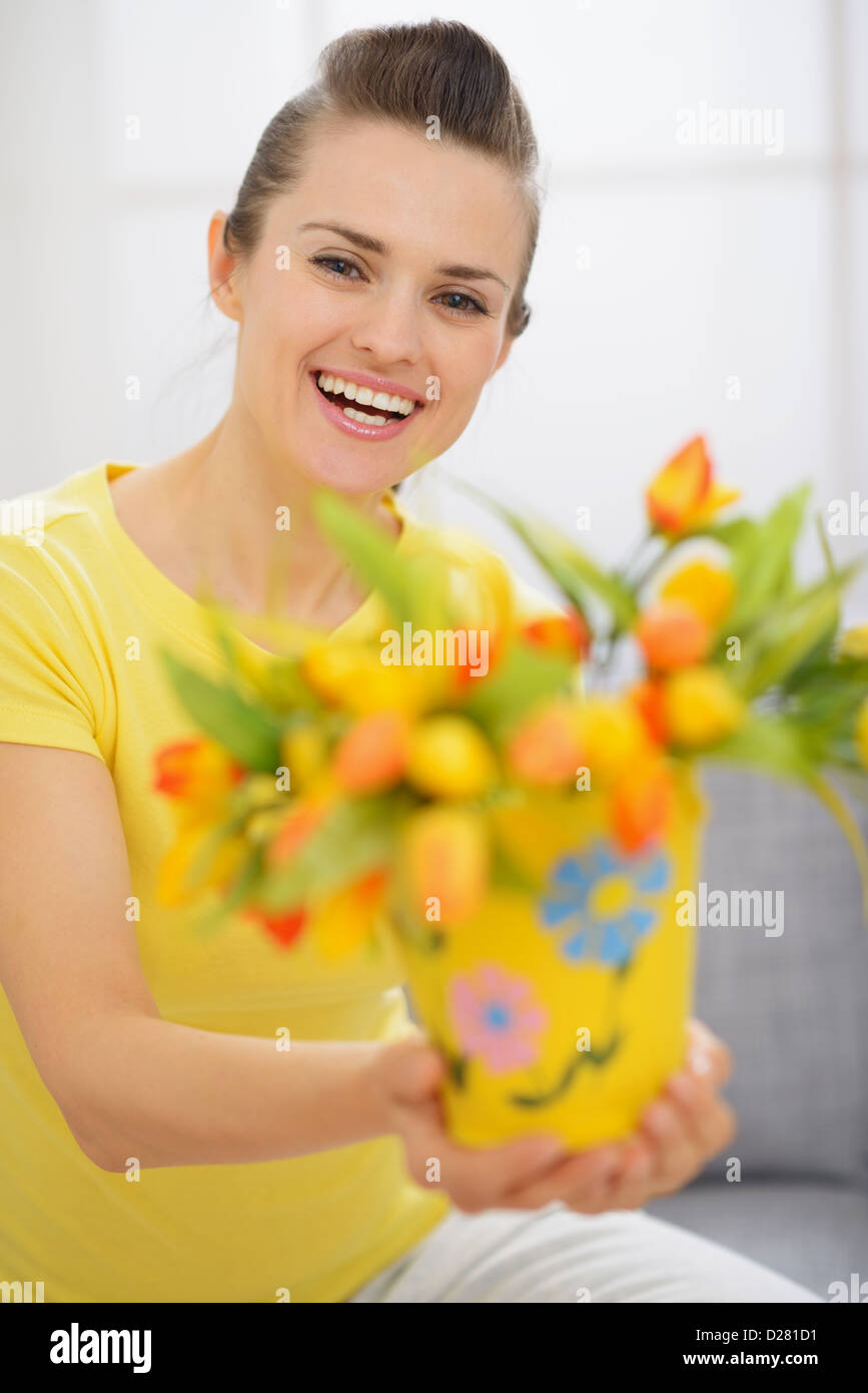 Happy young woman showing bouquet of tulips in bucket Stock Photo