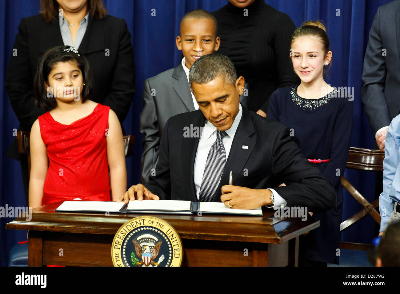 Jan. 16, 2013 - Washington, D.C, U.S. - With kids and parents whom after the Sandy Hook school shooting had written to the President asking for solutions to gun violence behind him, President BARACK OBAMA signs executive actions designed to curb gun violence. (Credit Image: © James Berglie/ZUMAPRESS.com) Stock Photo