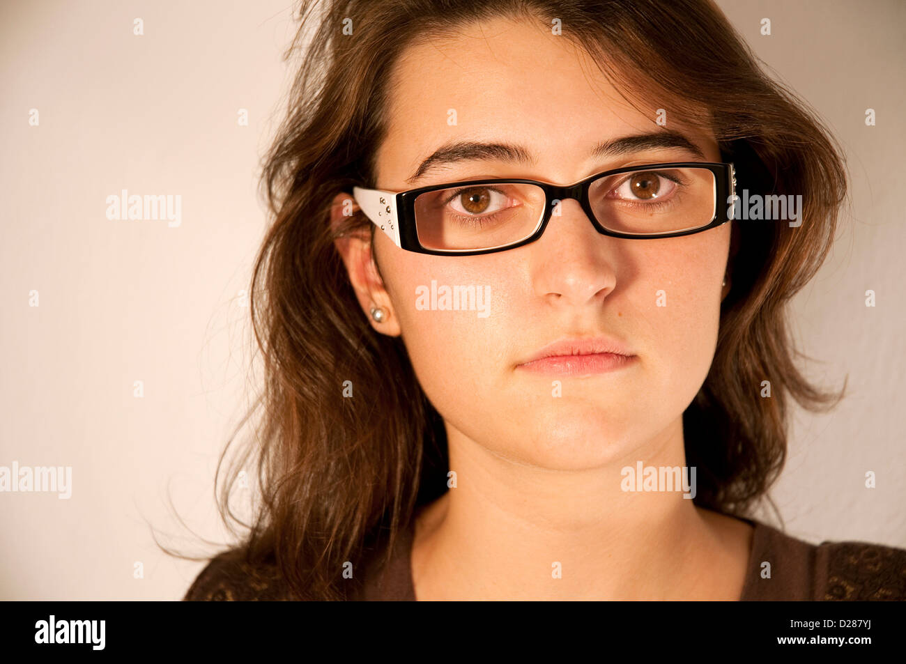 Young woman wearing spectacles, looking at the camera. Close view. Stock Photo