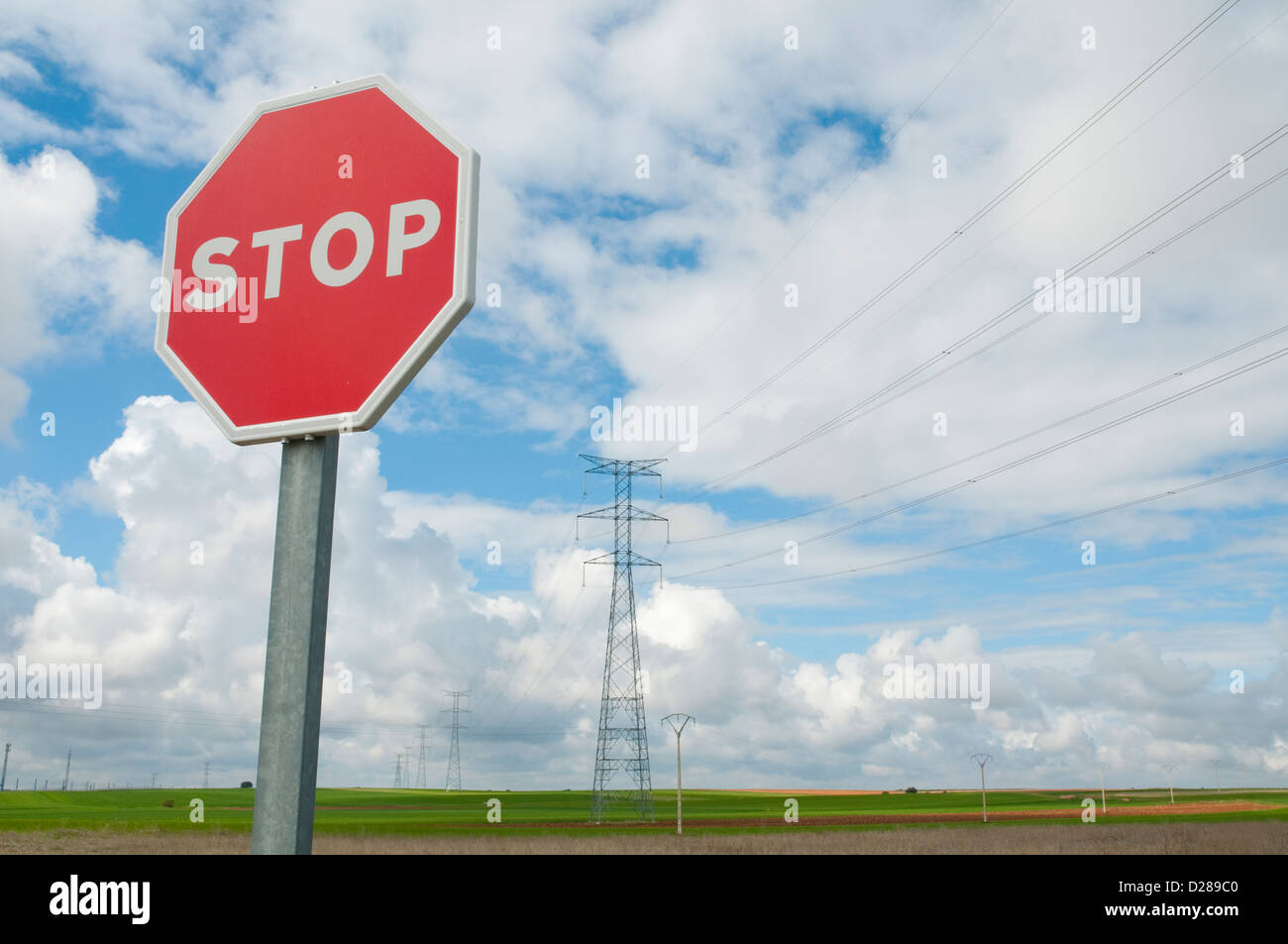 Stop traffic sign against cloudy sky, and landscape with power lines. Stock Photo