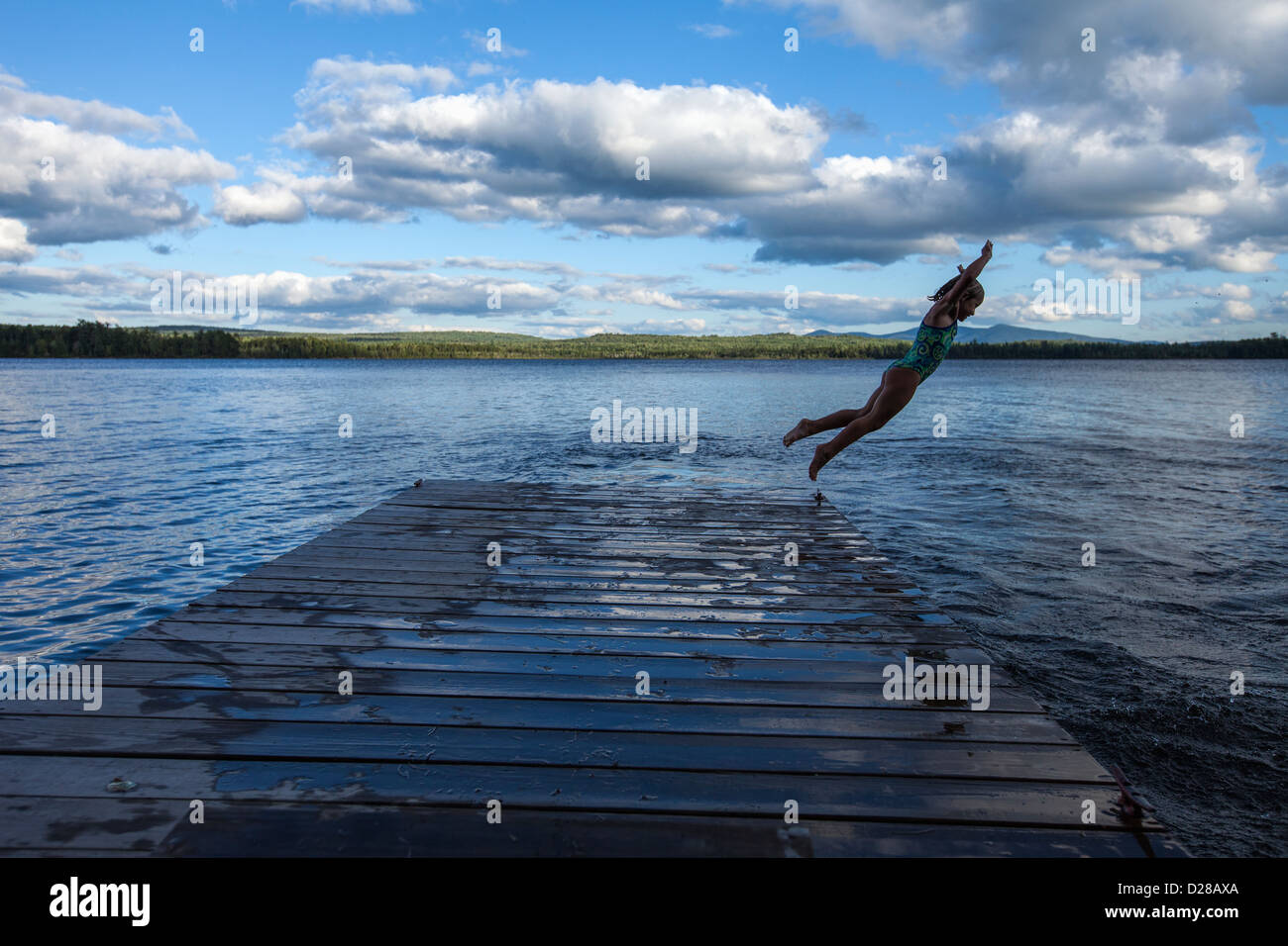 A young girl jumping off of a dock on a lake in Northern Maine Stock ...