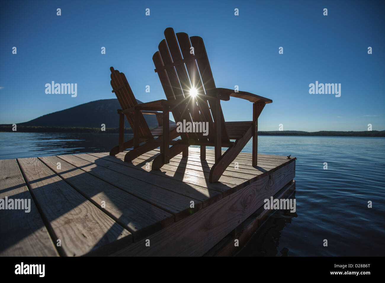 Two Adirondack chairs sitting on a dock on a lake in northern Maine