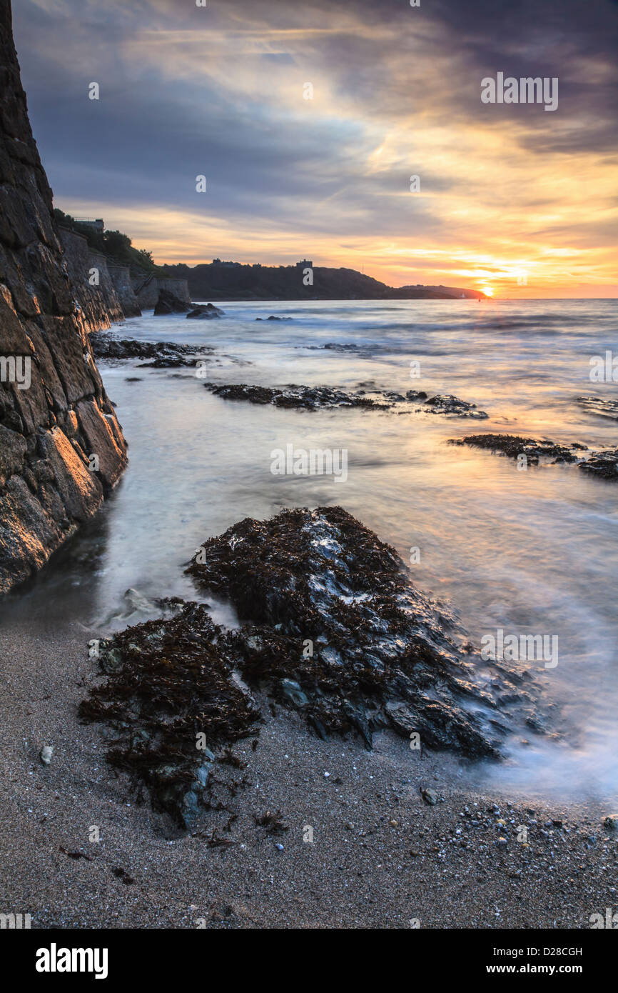 Sunrise captured from Falmouth's Gyllyngvase Beach , with Pendennis Castle in the distance. Stock Photo