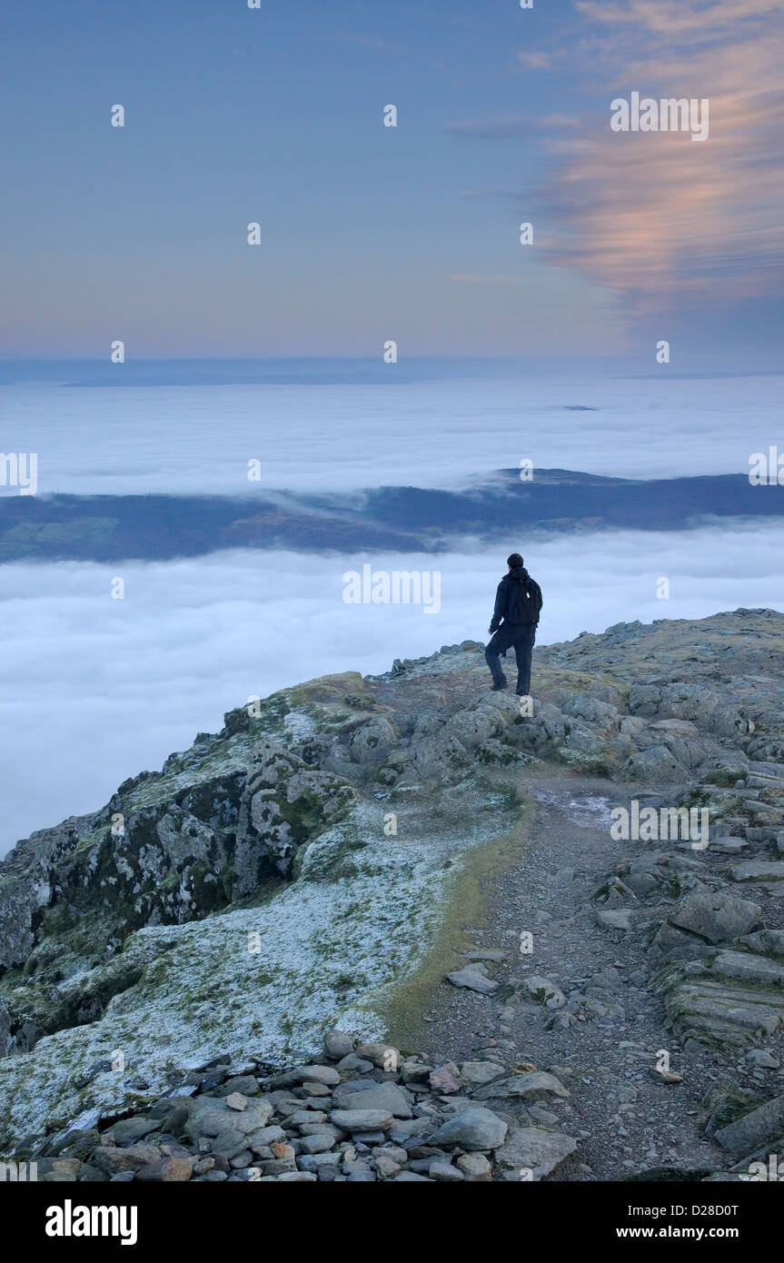 Lone walker on the summit of the Old Man of Coniston above a temperature inversion in the English Lake District Stock Photo