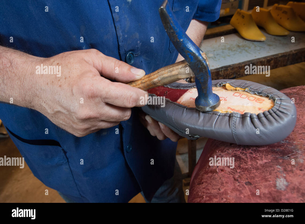 A shoe maker hammers the upper to the inner sole Stock Photo