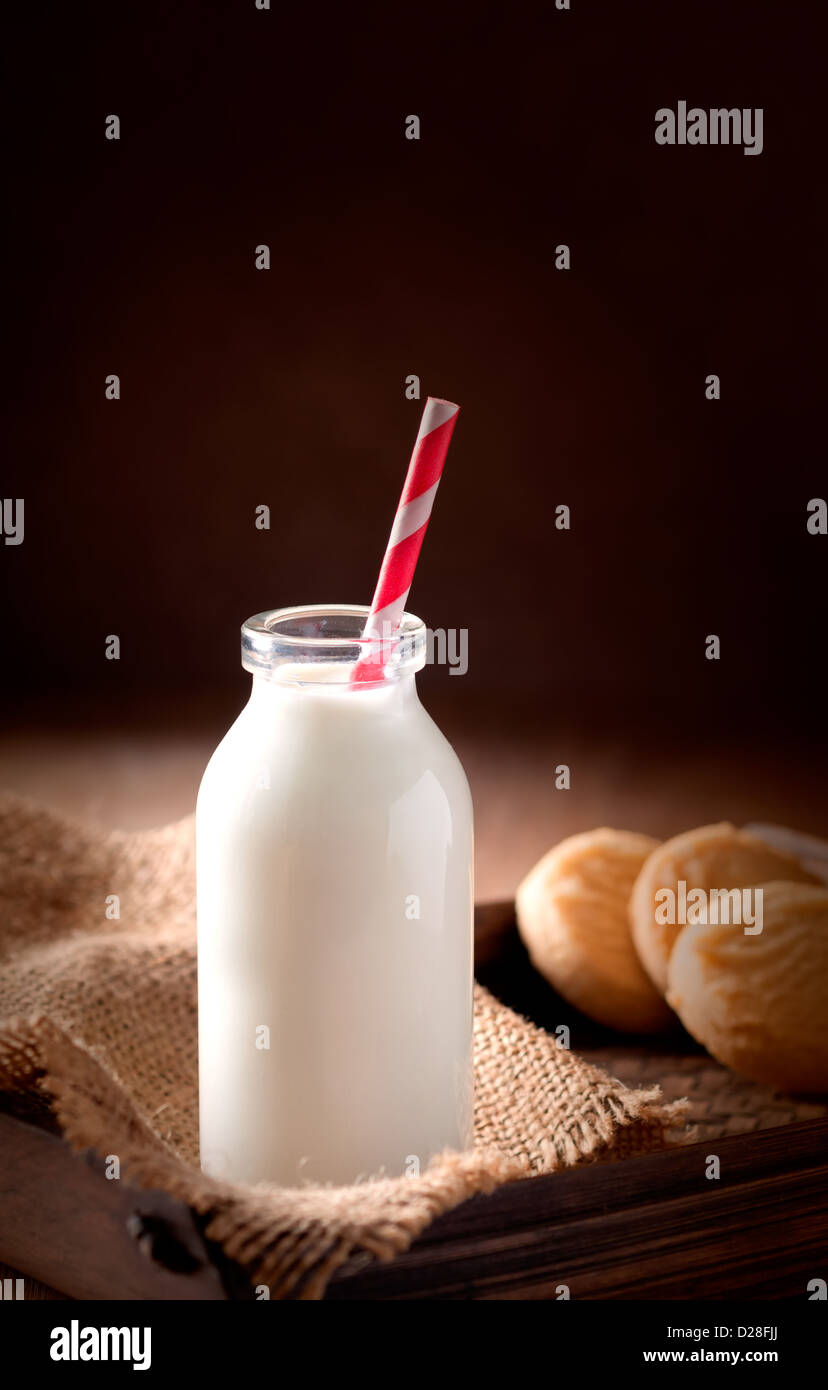 Bottle of milk with straw and shortbread cookies on tray Stock Photo