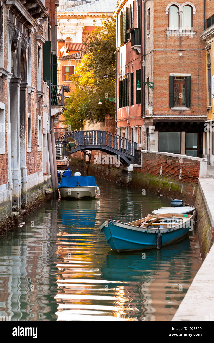 Bridge over a Venetian Canal and boats. Reflections are on the water ...