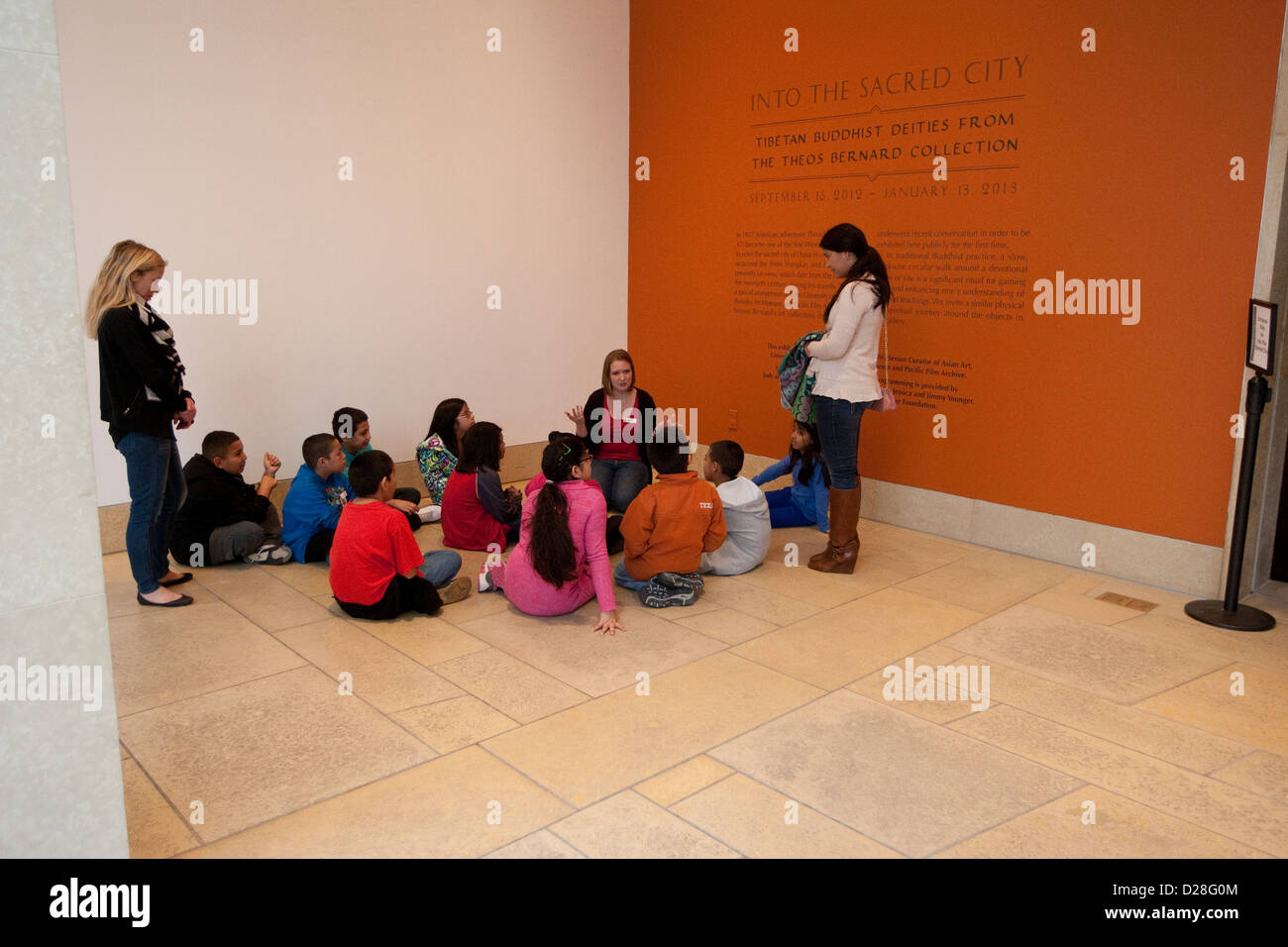 Group of elementary school age children sit in circle listening to teacher during a field trip to art museum in Austin, Texas Stock Photo