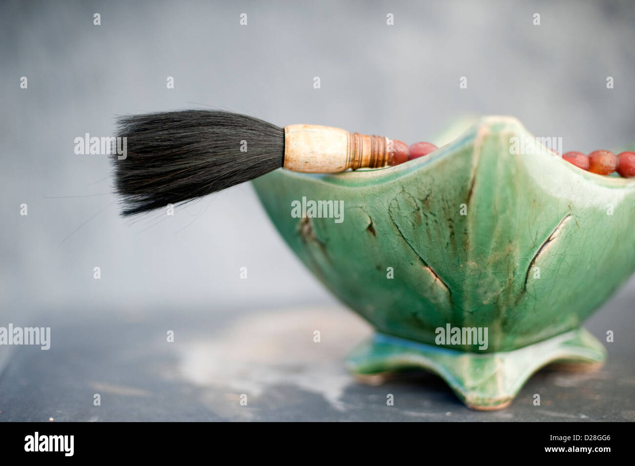 Still life of a traditional Chinese calligraphy brush propped on a bowl of stones. Stock Photo