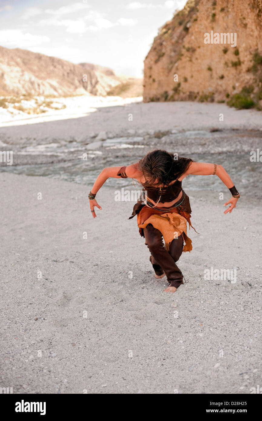 Woman dancing on the shore of a wild river with her arms held like bird wings. Stock Photo