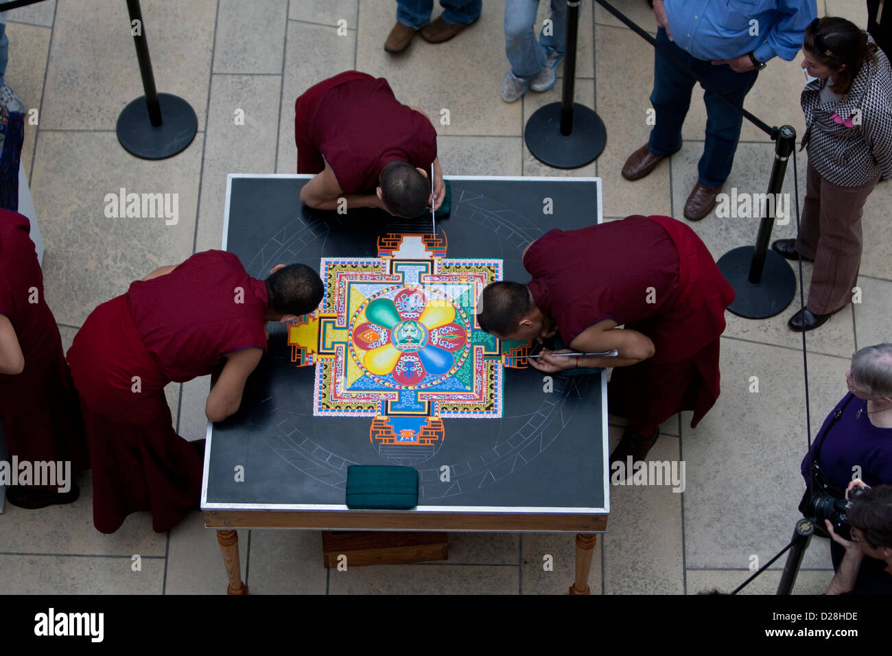 Tibetan Buddhist monks from the Drepung Loseling Monastery, construct an intricate, highly patterned large-scale sand mandala Stock Photo