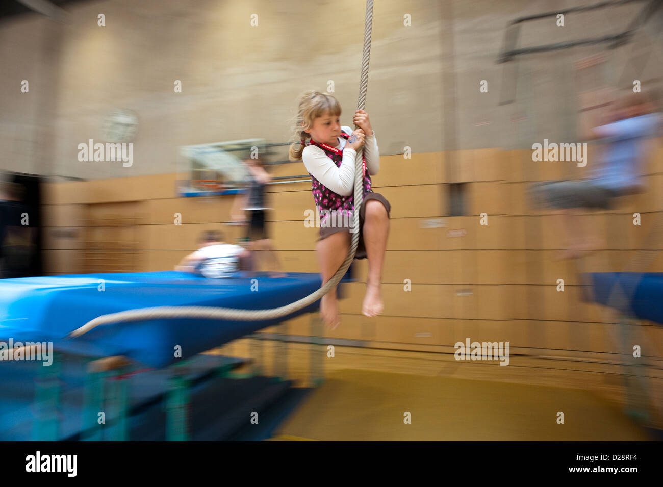 Berlin, Germany, blond girl swinging on a rope in a gymnasium Stock Photo