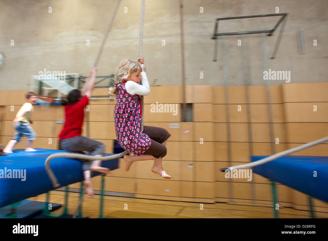 Berlin, Germany, blond girl swinging on a rope in a gymnasium Stock Photo