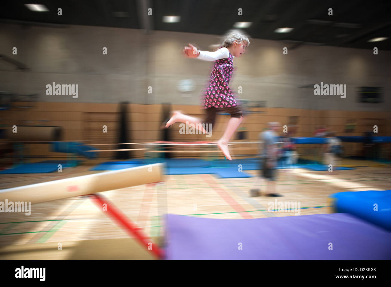 Berlin, Germany, blond girl jumps off a balance beam in a gym Stock Photo