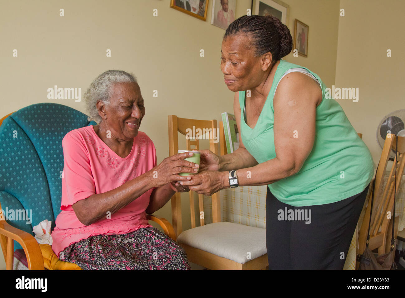 Carer giving elderly visually impaired woman a cup of tea Stock Photo