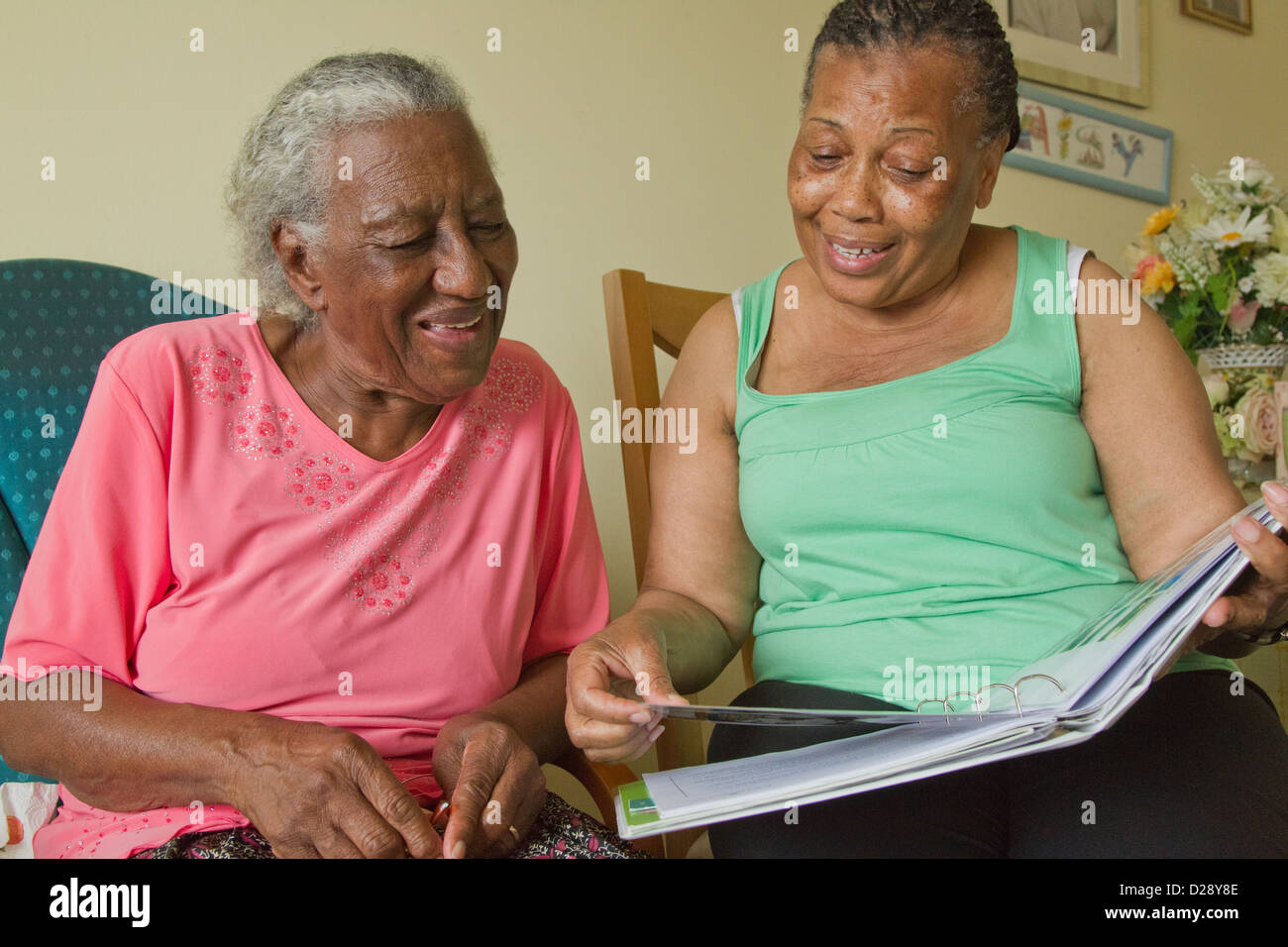 Carer and elderly visually impaired woman looking at photo album Stock Photo